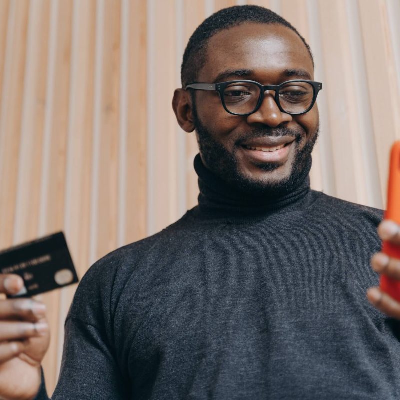 cheerful-african-american-businessman-holding-credit-card-and-smartphone-for-shopping-in-internet-1.jpg